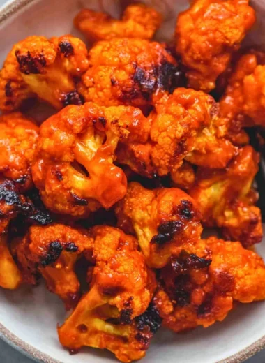 Plate of easy Buffalo Cauliflower with spicy sauce and fresh vegetables