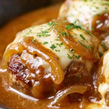Plate of French Onion Salisbury Steak topped with melted cheese and caramelized onions