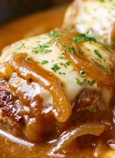 Plate of French Onion Salisbury Steak topped with melted cheese and caramelized onions
