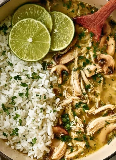 Bowl of Ginger Lime Chicken Soup with mushrooms and cilantro rice, garnished with lime.