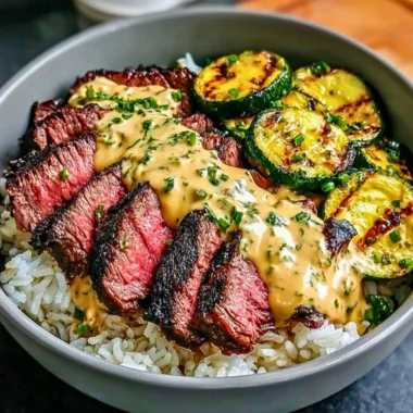 Delicious grilled steak bowl topped with sauce and grilled zucchini on a plate