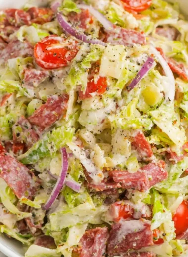 A colorful Italian Grinder Salad topped with fresh ingredients and dressing.