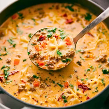 Bowl of Italian sausage pasta soup garnished with herbs and crusty bread
