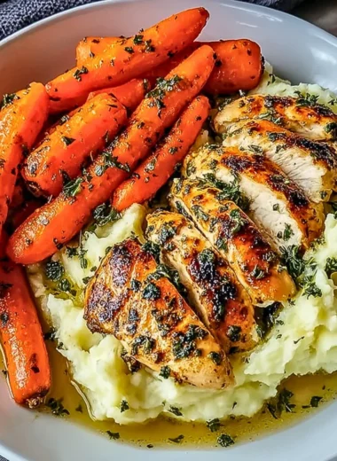 Plate of garlic herb chicken with mashed potatoes and glazed carrots.