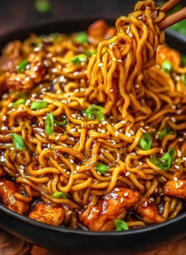 Plate of sticky garlic chicken noodles garnished with green onions