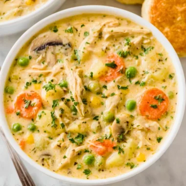 Creamy Chicken Pot Pie Soup in a bowl, garnished with herbs and vegetables.