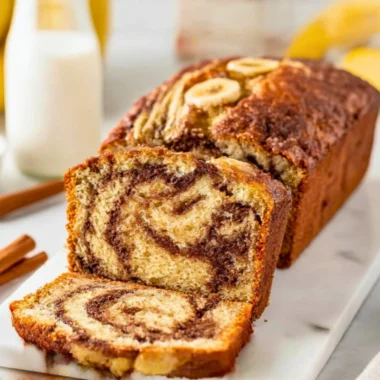 Sliced cinnamon swirl banana bread on a wooden cutting board