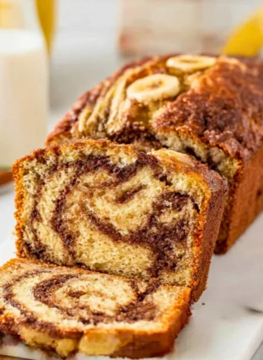 Sliced cinnamon swirl banana bread on a wooden cutting board