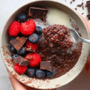 Dark chocolate quinoa breakfast bowl topped with fresh fruit and nuts