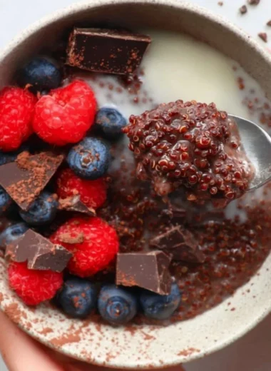 Dark chocolate quinoa breakfast bowl topped with fresh fruit and nuts