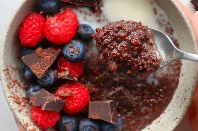 Dark chocolate quinoa breakfast bowl topped with fresh fruit and nuts