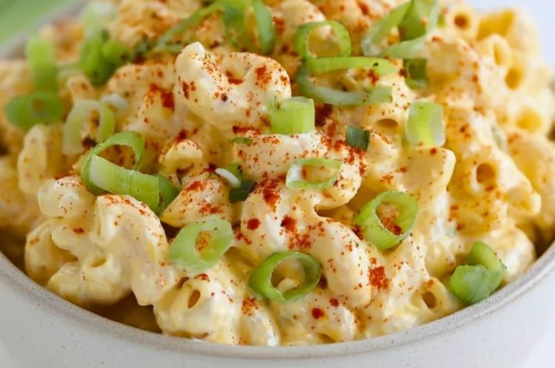 A bowl of Deviled Egg Pasta Salad with eggs, pasta, and herbs