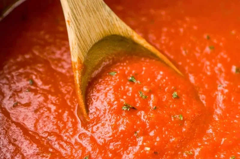 Bowl of homemade marinara sauce with fresh basil and tomatoes