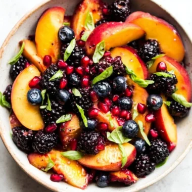 A vibrant bowl of Honey Lime Basil Peach Fruit Salad.