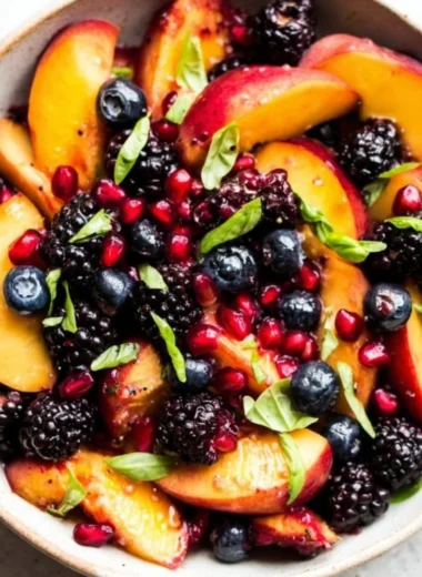 A vibrant bowl of Honey Lime Basil Peach Fruit Salad.