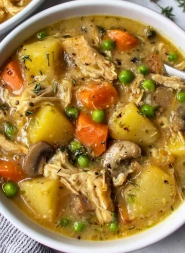 Bowl of slow cooker chicken stew with vegetables and herbs