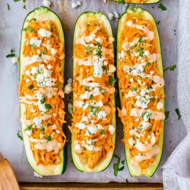 Buffalo chicken stuffed zucchini boats topped with cheese and herbs