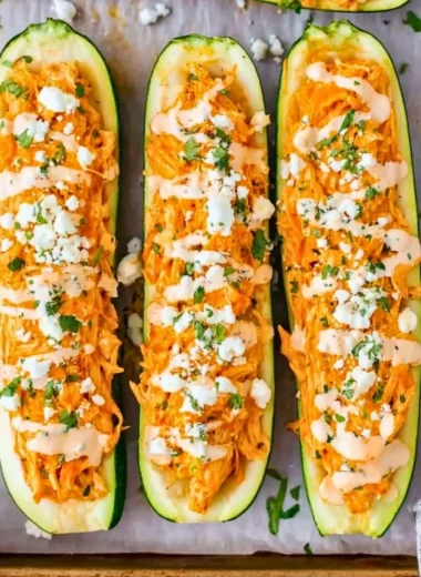 Buffalo chicken stuffed zucchini boats topped with cheese and herbs