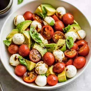 Light avocado caprese salad with fresh mozzarella, tomatoes, and basil.
