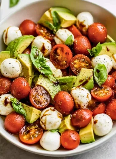 Light avocado caprese salad with fresh mozzarella, tomatoes, and basil.