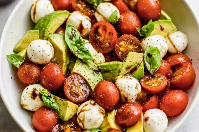 Light avocado caprese salad with fresh mozzarella, tomatoes, and basil.