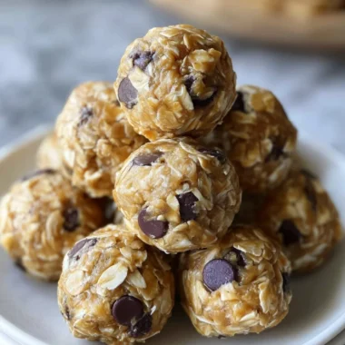 No-bake peanut butter energy bites on a white plate topped with oats and chocolate chips.