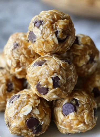 No-bake peanut butter energy bites on a white plate topped with oats and chocolate chips.