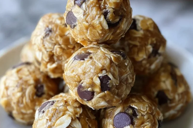 No-bake peanut butter energy bites on a white plate topped with oats and chocolate chips.