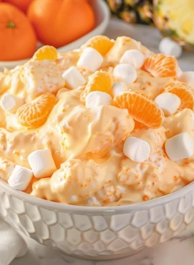 A bowl of light and fluffy Orange Fluff Salad with fresh oranges and whipped cream.