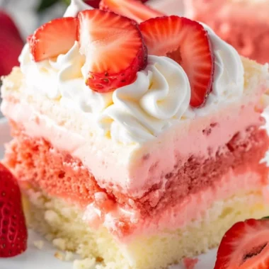 Close-up of a slice of Strawberry Cheesecake Poke Cake on a plate.
