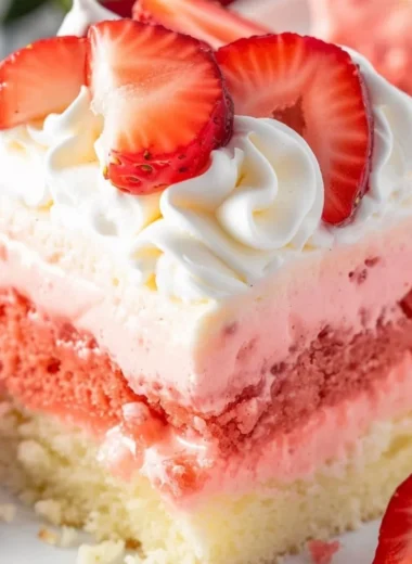 Close-up of a slice of Strawberry Cheesecake Poke Cake on a plate.