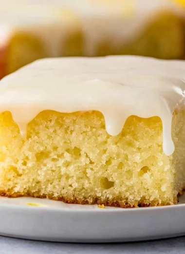 Delicious homemade lemonade poke cake with lemon icing on a serving plate.