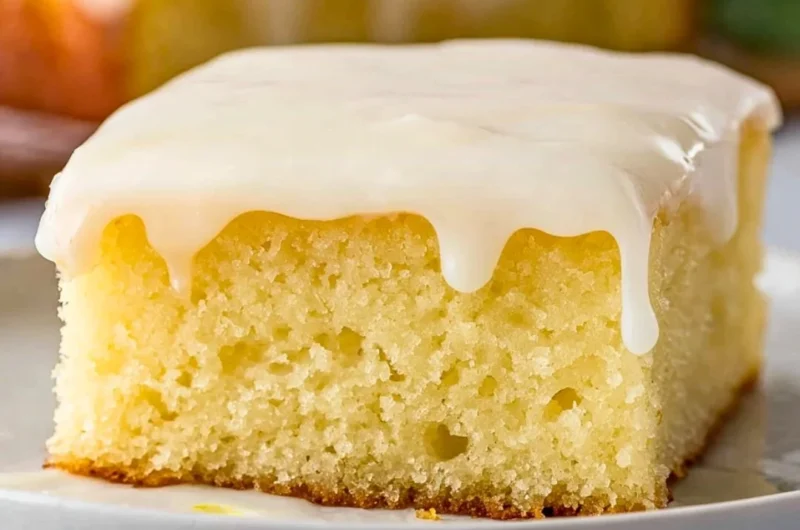 Delicious homemade lemonade poke cake with lemon icing on a serving plate.