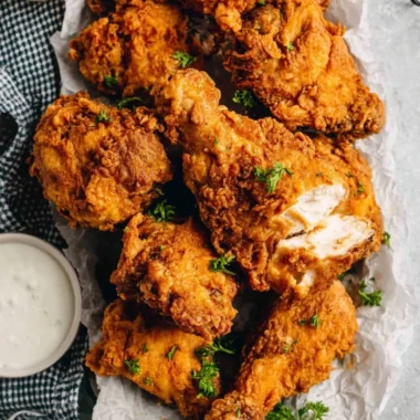 Plate of crispy buttermilk fried chicken garnished with herbs
