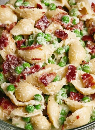 Creamy pea bacon pasta salad served in a bowl with fresh ingredients.