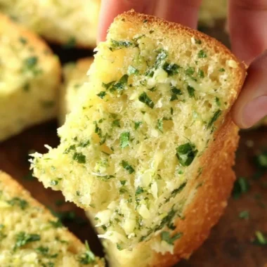 Sliced homemade garlic bread with herbs and butter on a wooden board