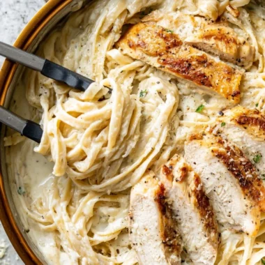 Creamy Chicken Fettuccine Alfredo served with fresh herbs and parmesan cheese