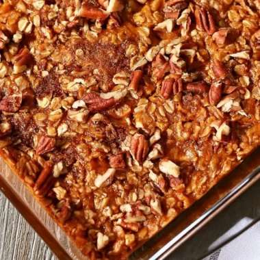 A bowl of Pumpkin Pecan Baked Oatmeal topped with nuts and spices