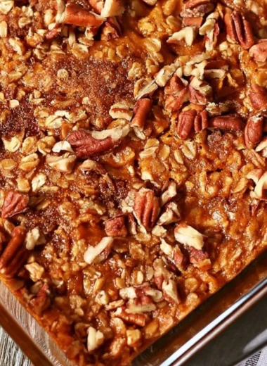 A bowl of Pumpkin Pecan Baked Oatmeal topped with nuts and spices